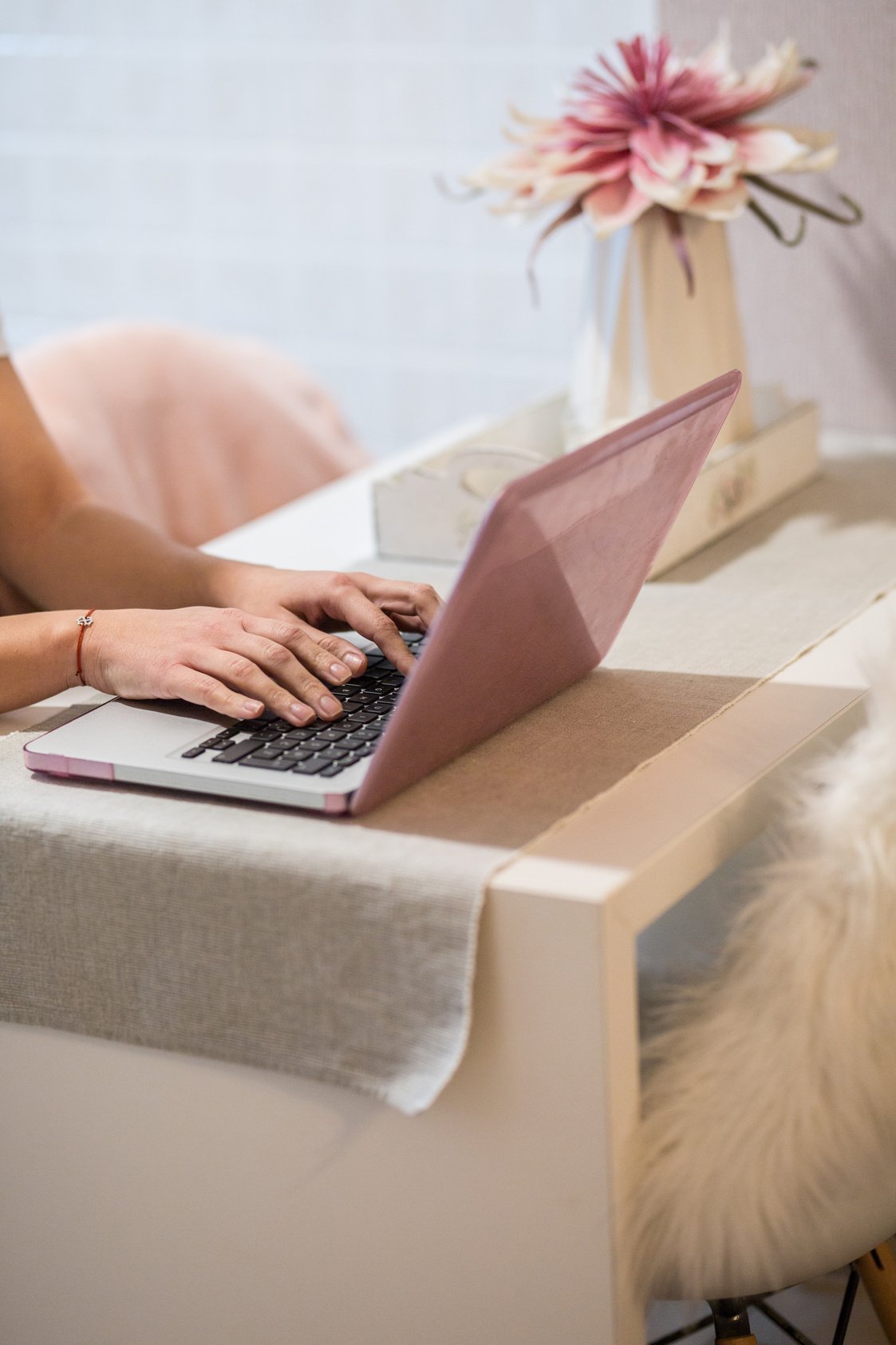 Hands typing on pink laptop